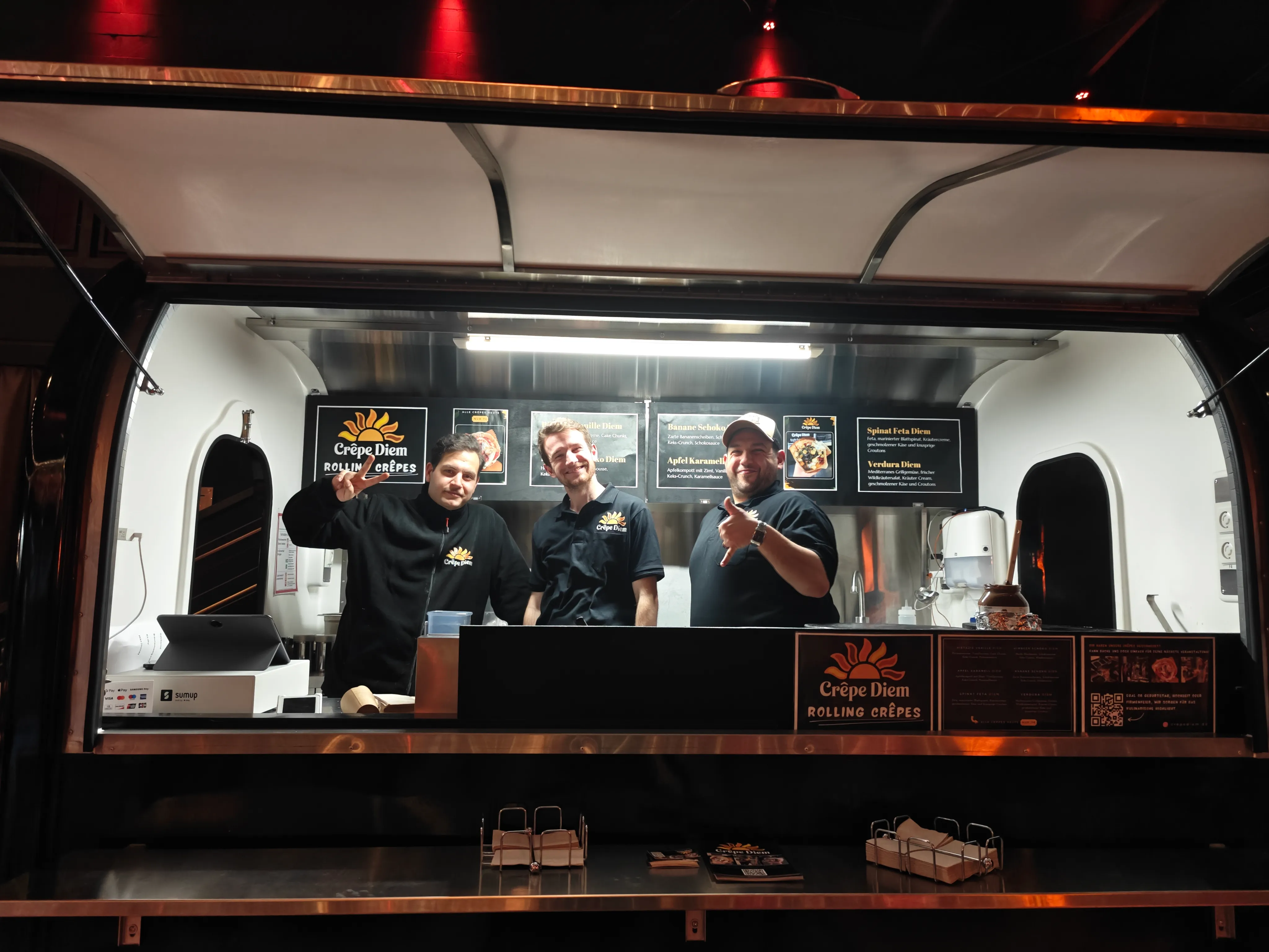 Das Crêpe Diem Team im Foodtruck – drei lächelnde Mitarbeiter bereit für den Service